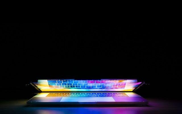 Stylised photograph of a laptop opening and coloured light emerging