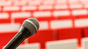 A microphone against a blurred backdrop of seats in a lecture theatre