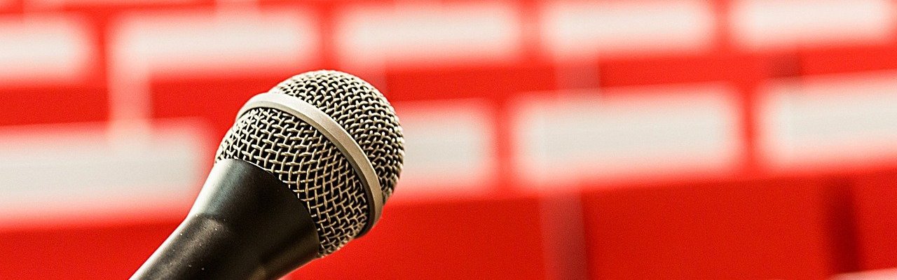 A microphone against a blurred backdrop of seats in a lecture theatre