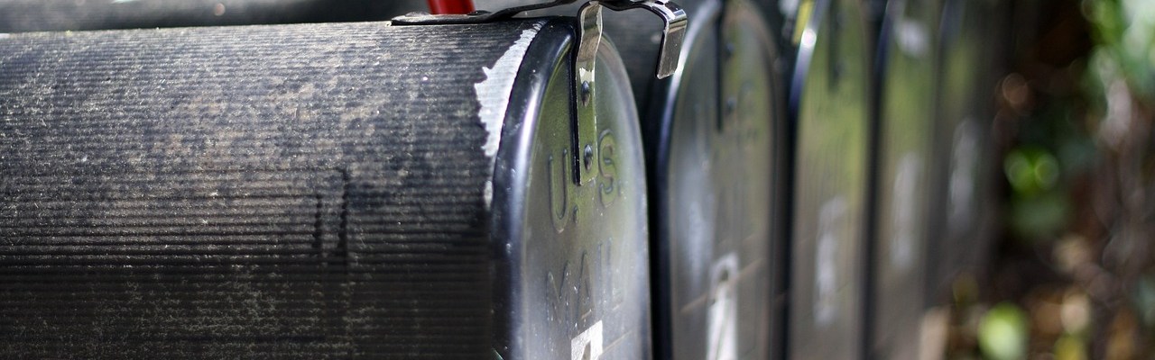 A series of grey metal mailboxes, one has a red flag raised indicating new messages.