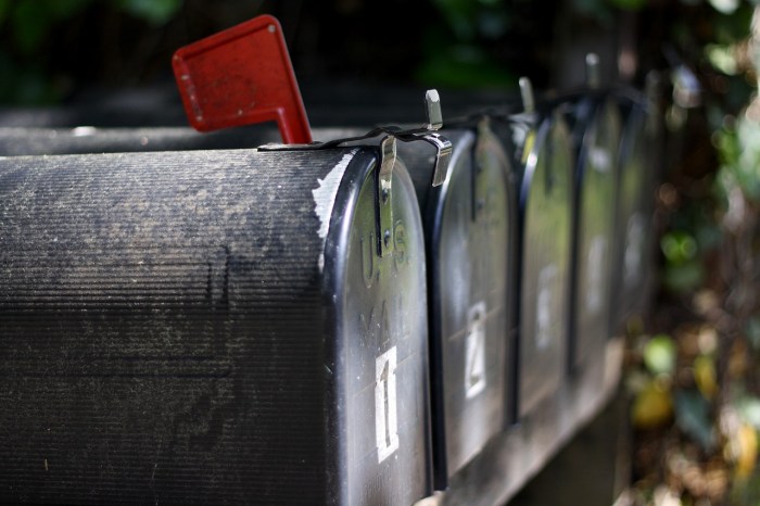 A series of grey metal mailboxes, one has a red flag raised indicating new messages.