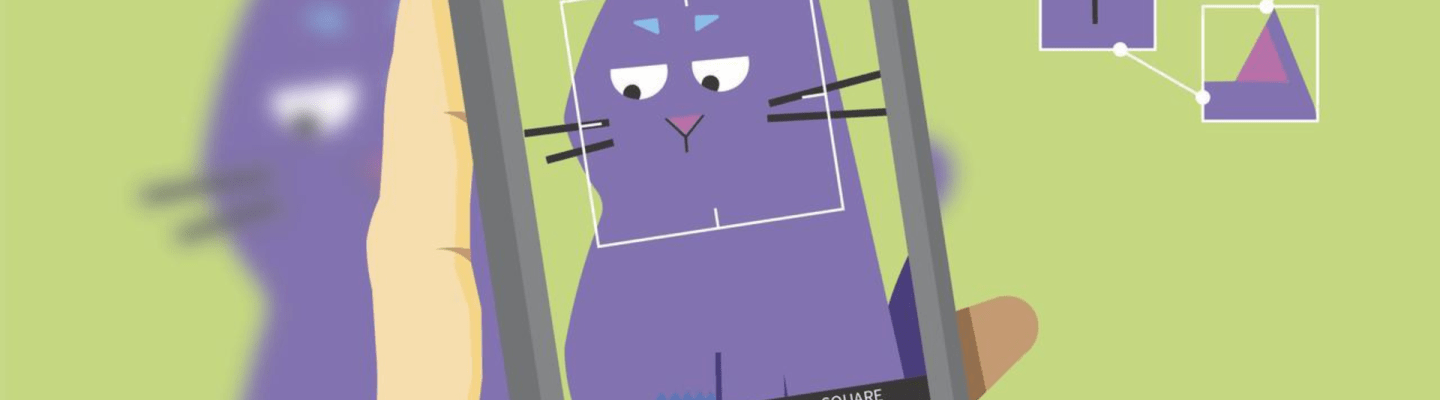 An illustration showing a hand holding a smartphone with its camera app open, capturing an image of a cartoon purple cat. The camera screen displays the cat framed with a square outline, and several facial features—such as the eyes, ears, and nose—are highlighted with smaller boxes and connected by thin lines, illustrating an AI recognition process. The cat is slightly blurred in the background outside the phone screen, emphasising the focus on the camera's view.